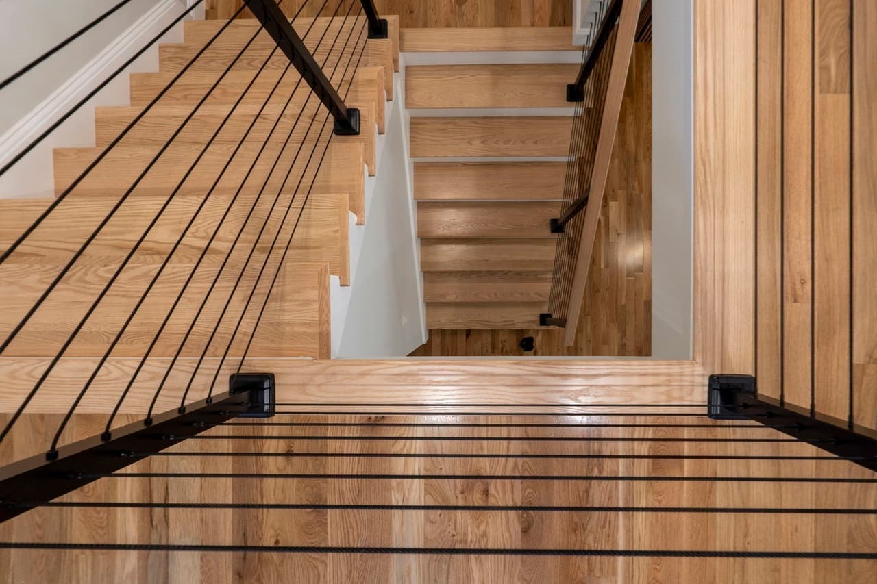 Open cable-rail staircase with slat-wood accent wall
